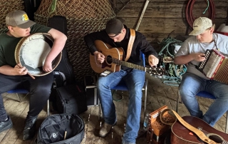 The three members of Salt Beef Junkies playing music in a fishing hut.