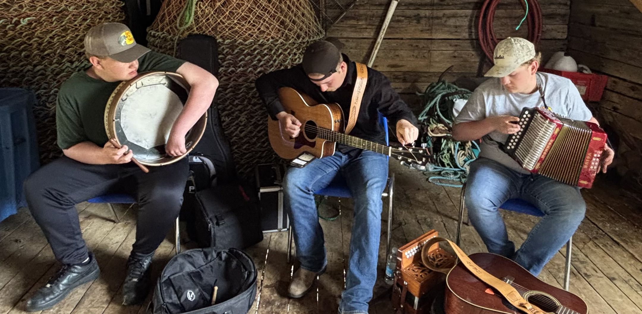 The three members of Salt Beef Junkies playing music in a fishing hut.